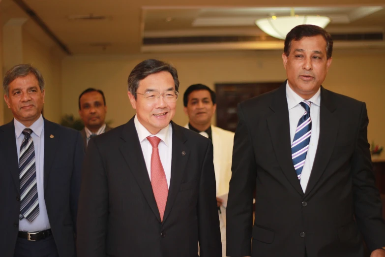 four men in suits walking into a building