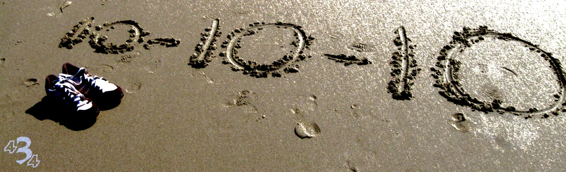 person with feet on wet sand and one hand written in the sand