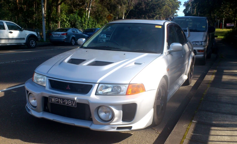 a white car parked on a street with other cars