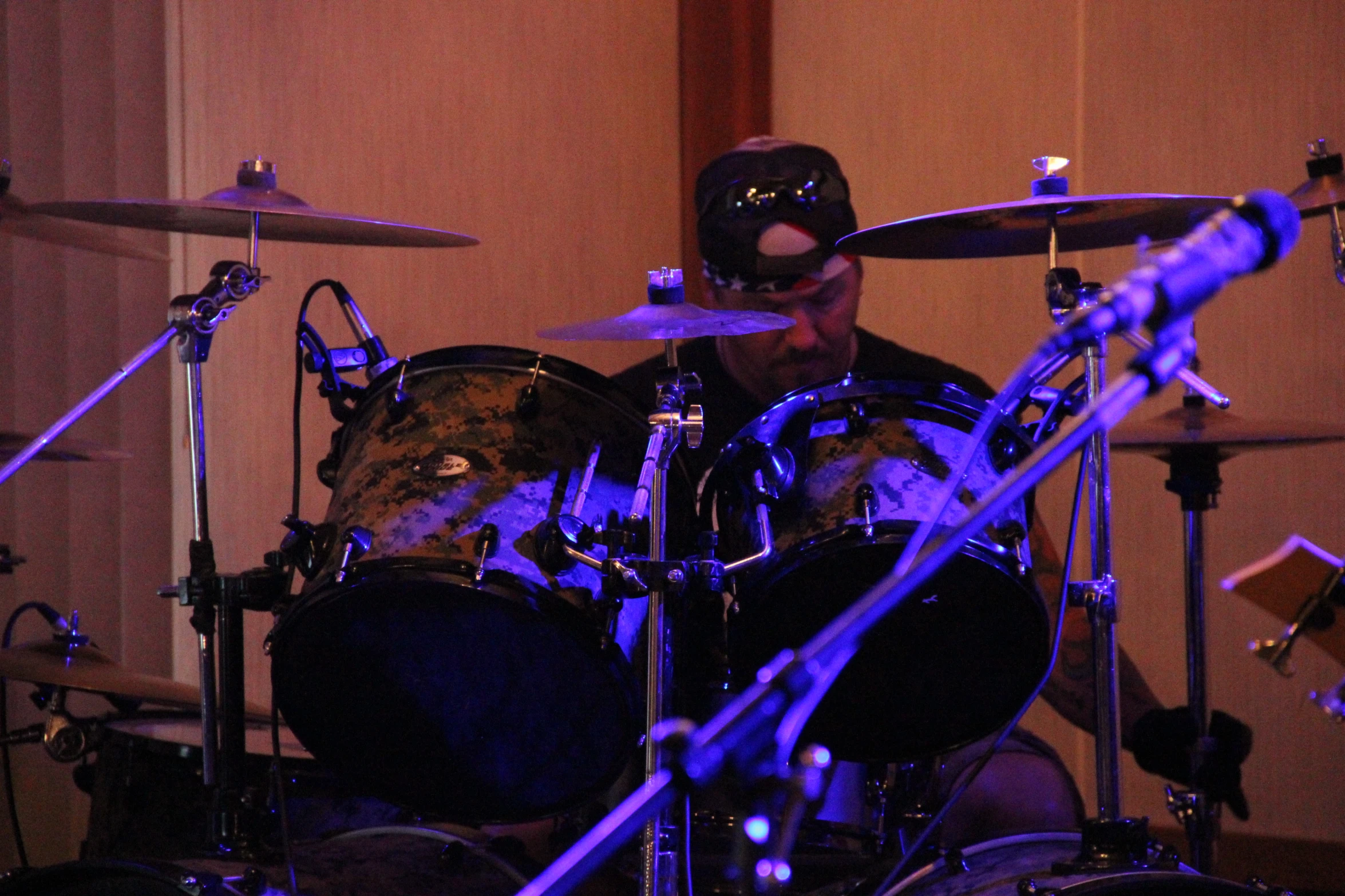 man sitting in front of drums on stage playing a song