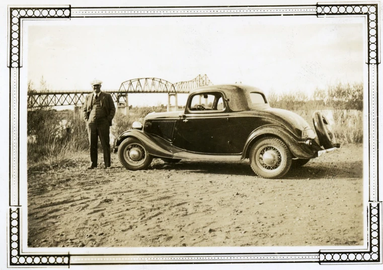 a black and white po with a man standing next to an antique truck