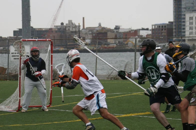 a group of young men playing lacrosse on an outside court