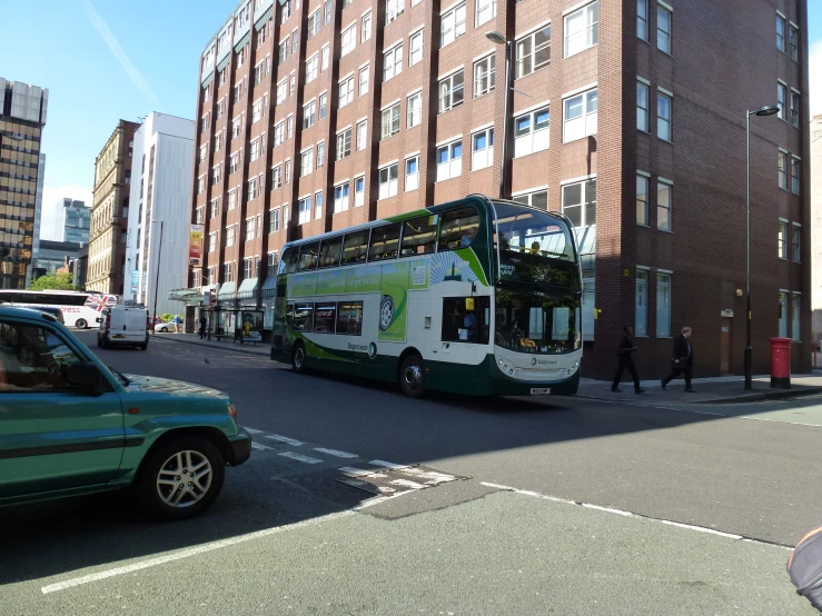 a double decker bus is on the road by a building