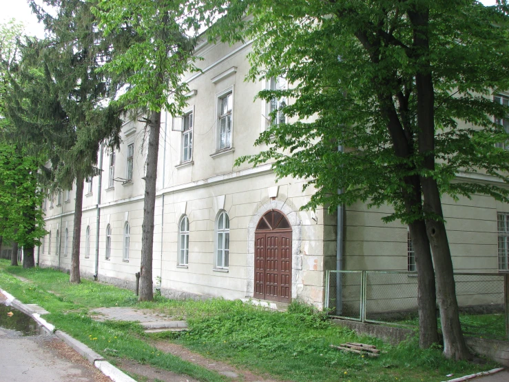 an old white building with trees surrounding it