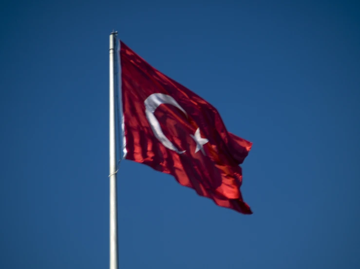 the flag of turkey with a crescent and star is flying high