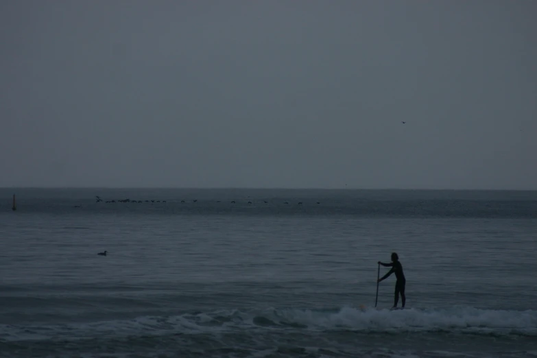 a man standing on a surfboard while holding his stick