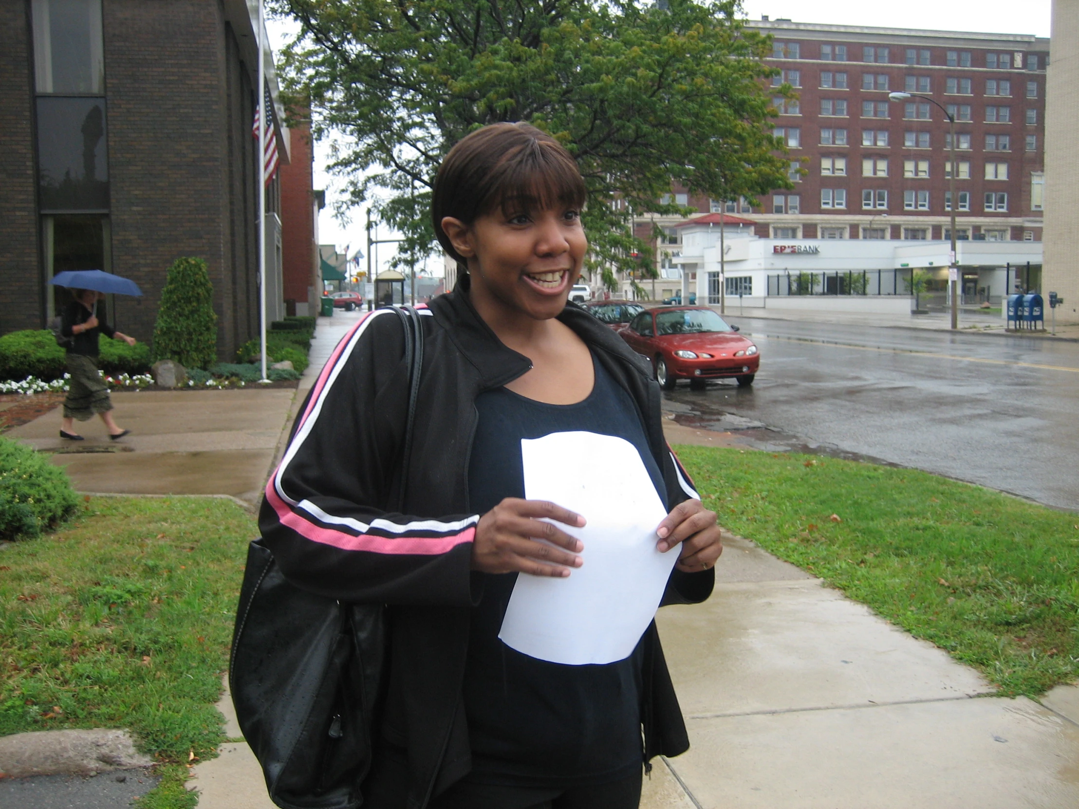 a black woman holds a paper and smiles