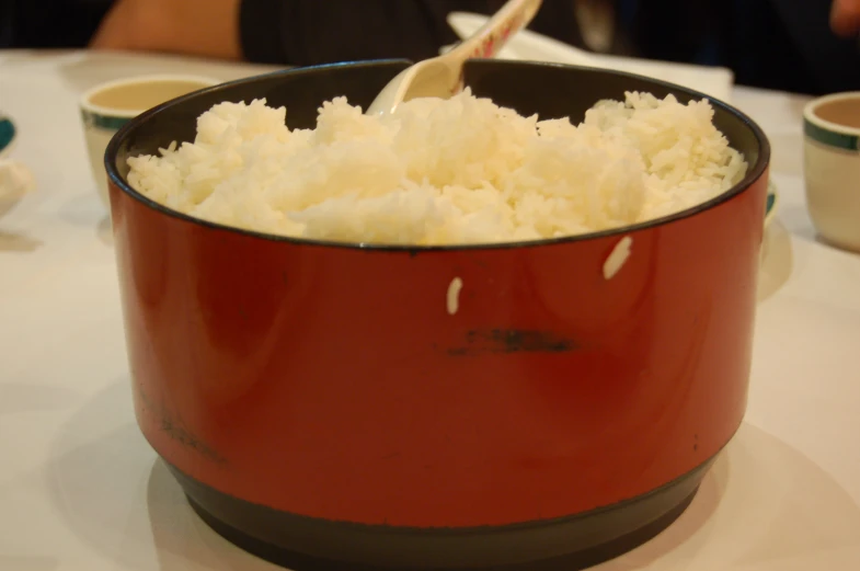 a big pot with white rice and some spoon in it