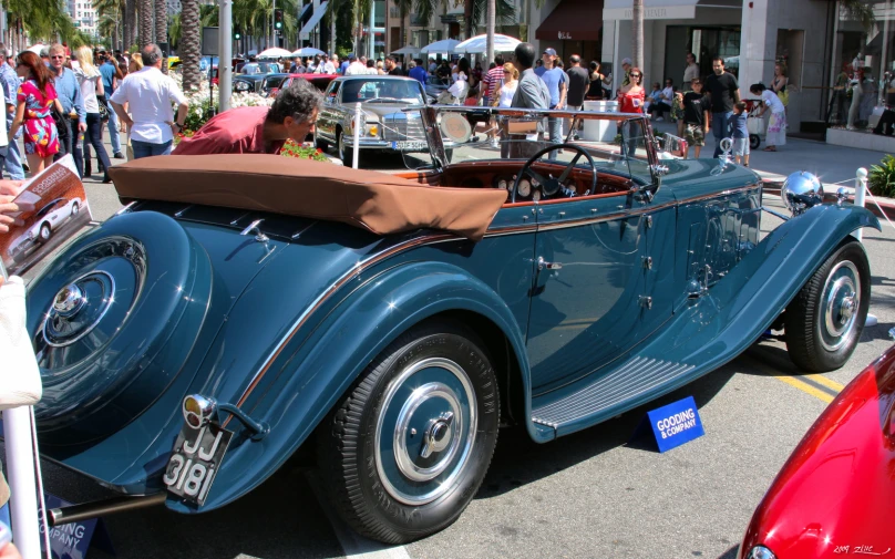 an old fashioned car sits parked on the side of the street