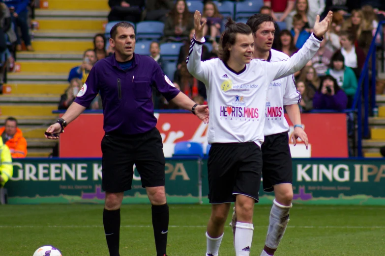 two men are being congratulated by referee at a soccer match