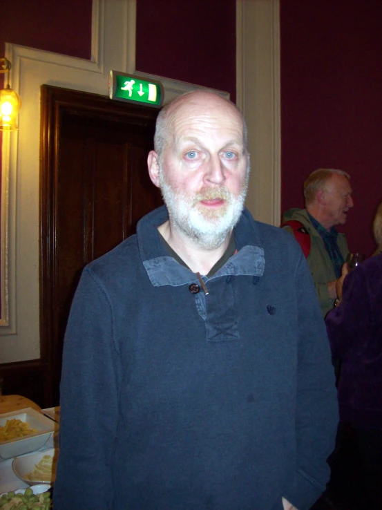 an older man with white beard wearing a blue sweater