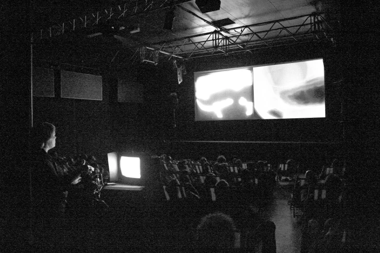 the audience watches a screen with people standing in it