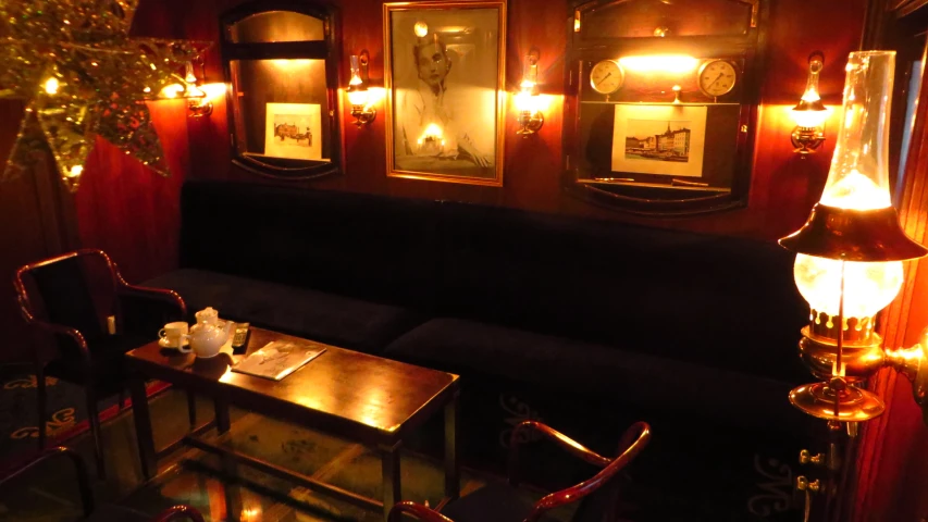 a dining area with table, bench, lamps and pictures