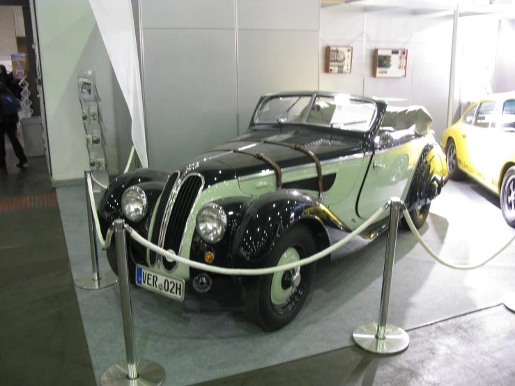 an old fashioned black and white car parked next to some people