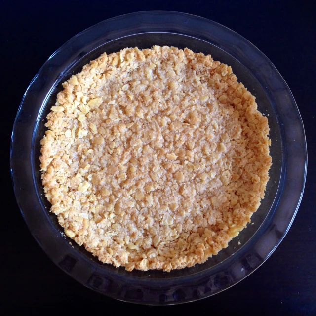 a pie crust in a glass dish on a black table