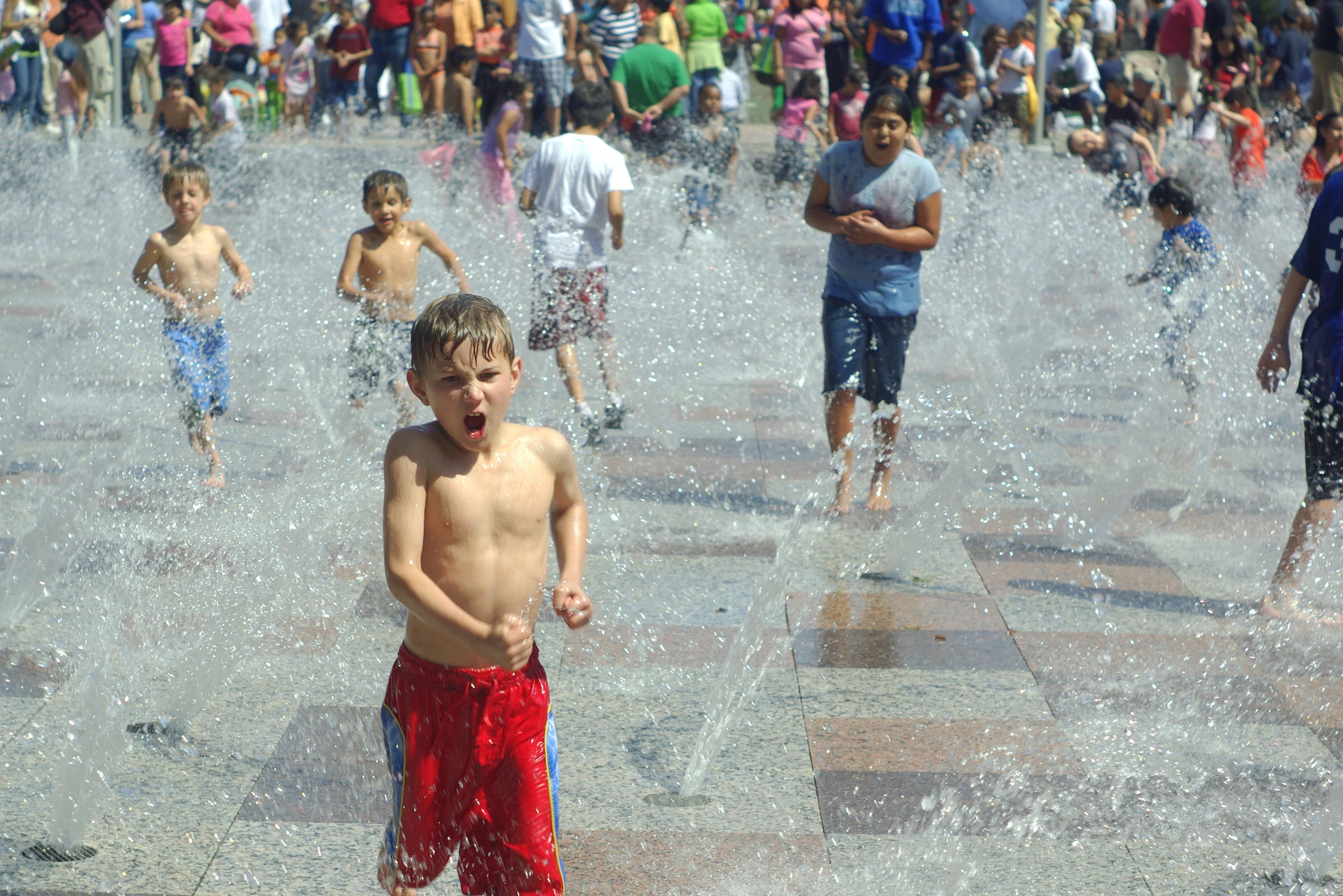 boys standing and walking around in the water fountains