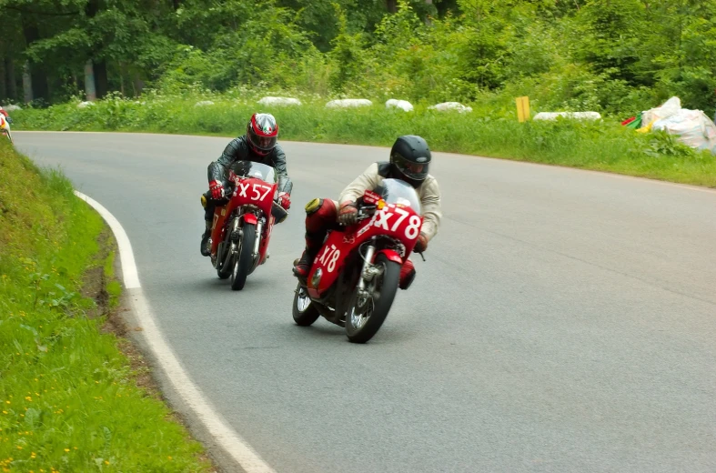 two people on motorcycles riding down the road