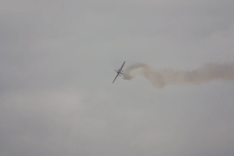 an airplane is flying high in the air leaving smoke behind