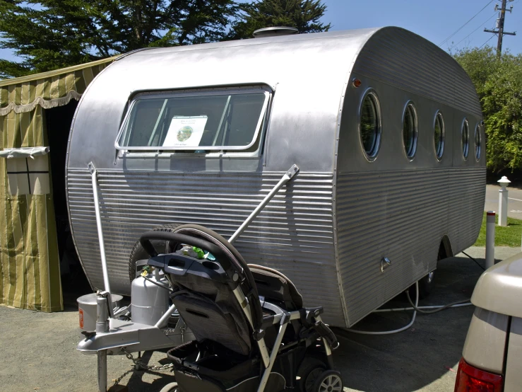 an outdoor camper next to a trailer on a gravel area