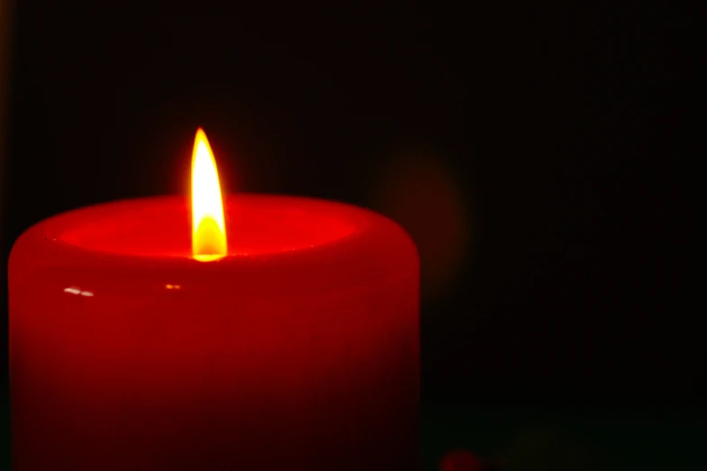 a lit red candle glowing in the dark