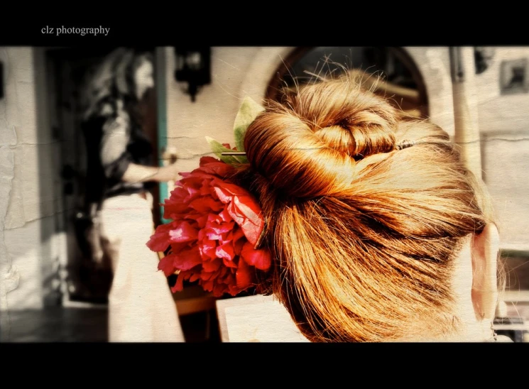 a woman's hair in a bun with red flowers in it