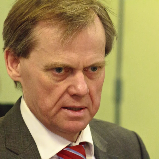 a man with a tie is sitting and looking down