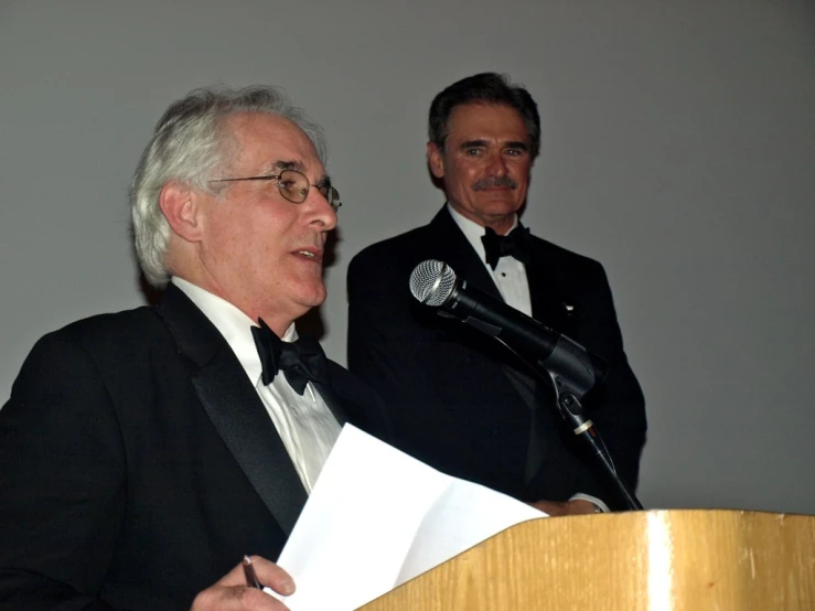 an older man standing at a podium talking