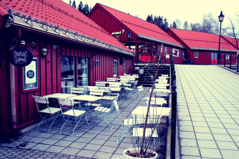 several tables and chairs outside of red building