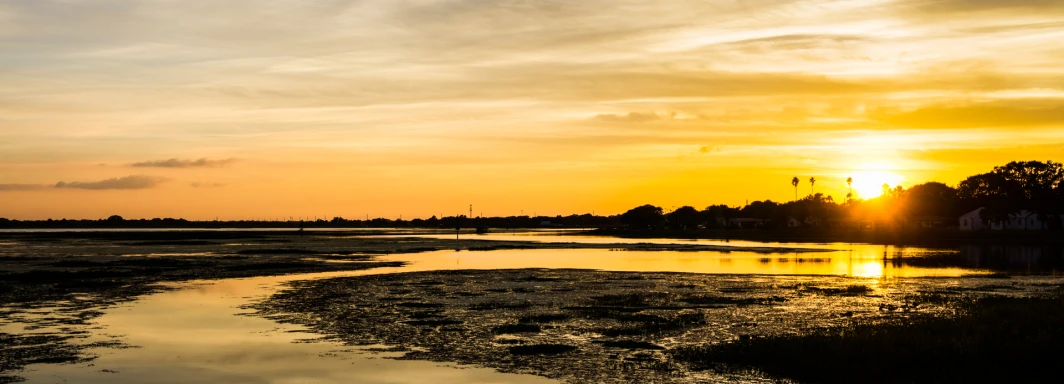 a sunset over the water with a boat in it