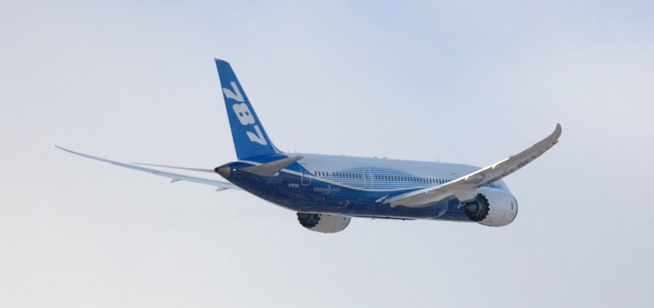 a blue and white plane flying in the sky