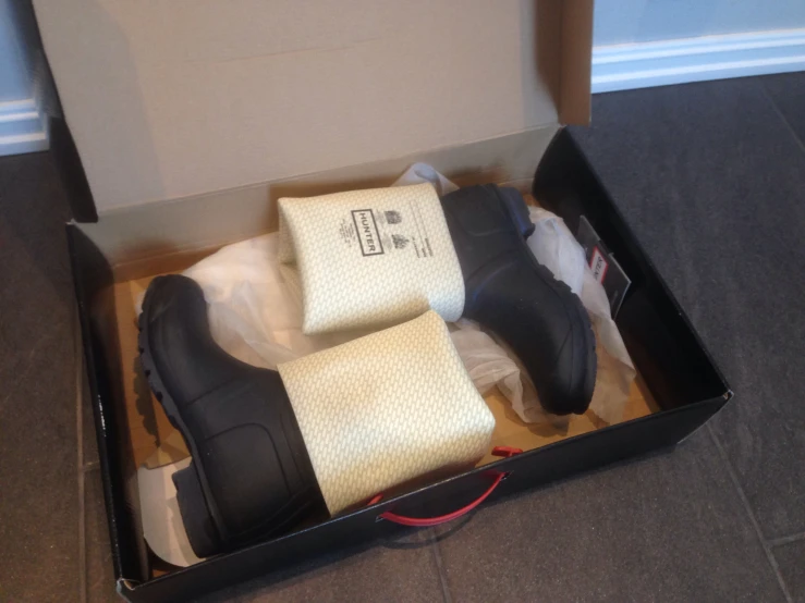 a box holding several boots in it sitting on the ground