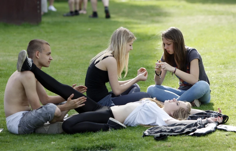 three people sitting and eating in a field