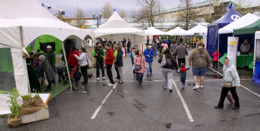 a group of people walking around tents with white roofing