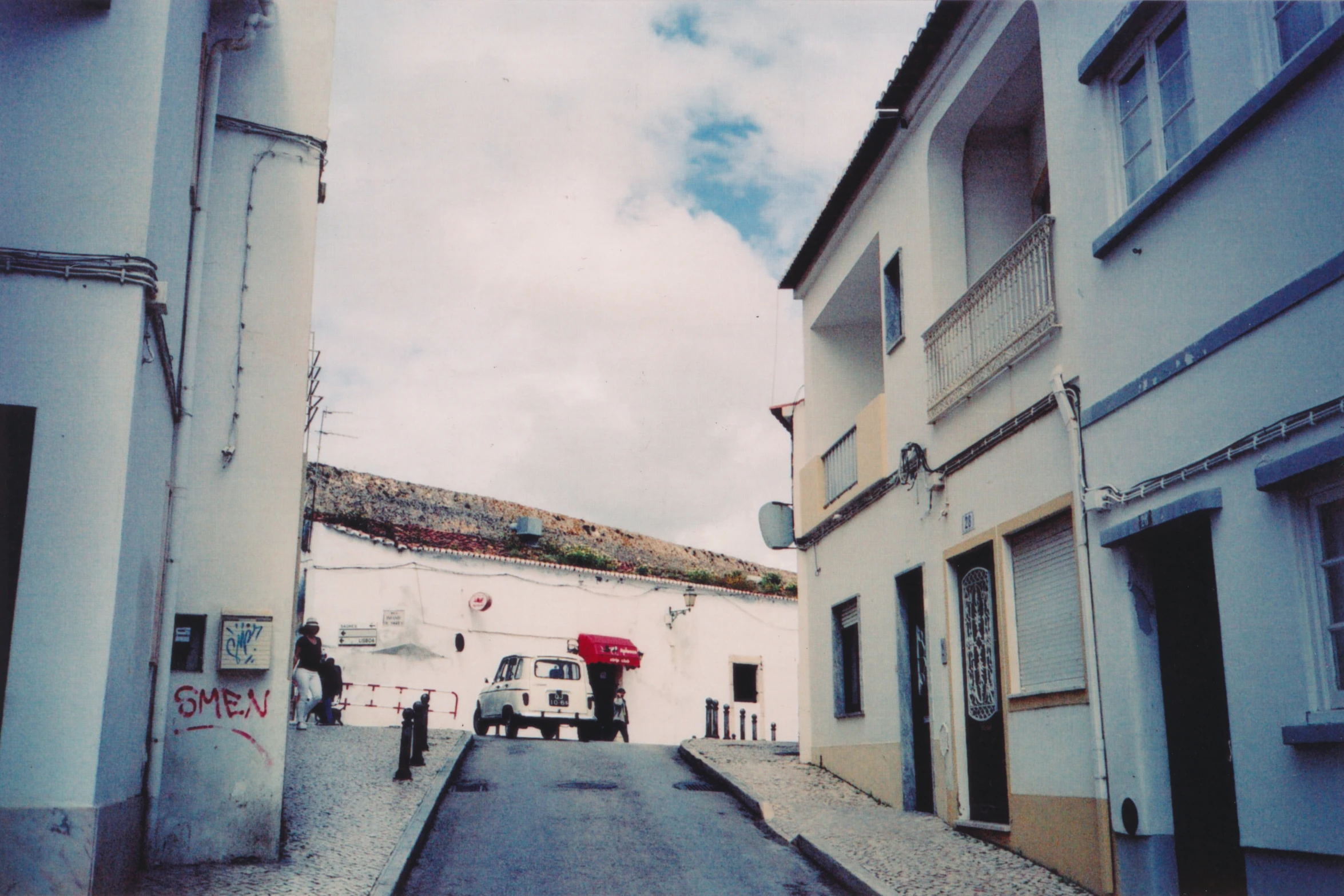 a narrow street with cars parked along the side