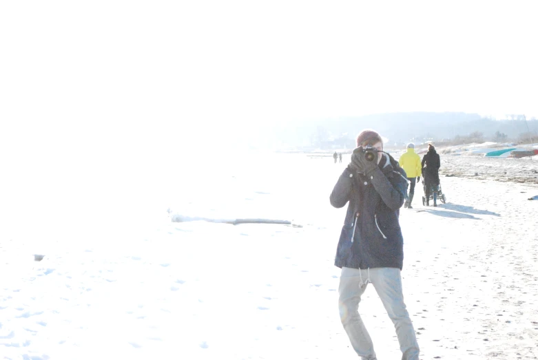 people walking on the beach while a man holds up his cell phone to his ear