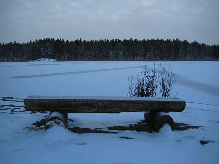 a bench in the snow near a field