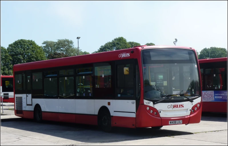 a red and white bus sitting at a bus stop