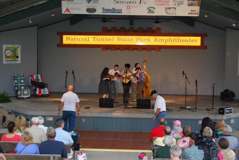 group of people on stage with microphones performing