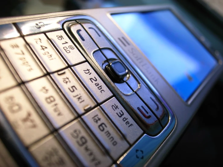 a close up of a small silver cellphone with small screen holes