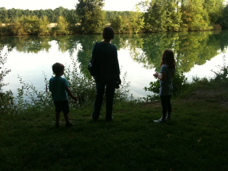 a man and two children on the grass next to water