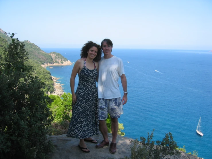 two people standing next to each other in front of the water