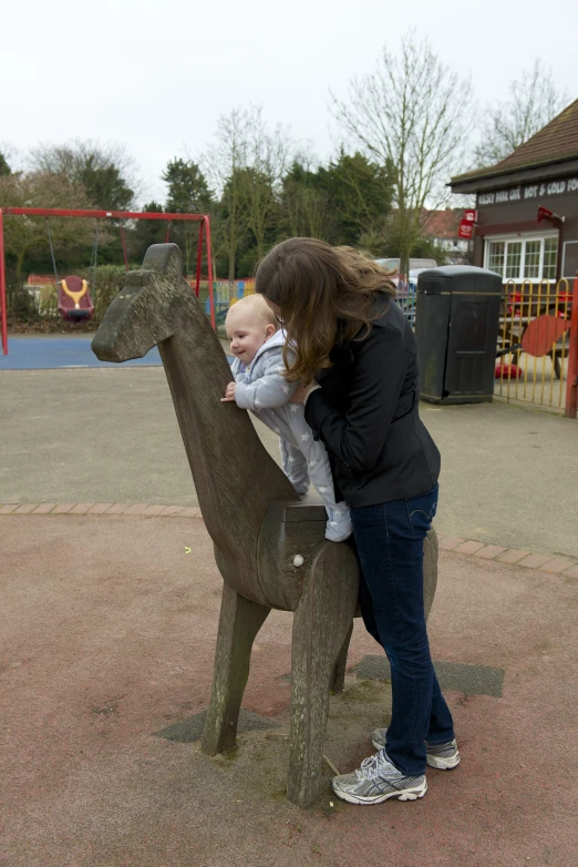 a woman with a baby in her arms standing next to a statue of a fawness