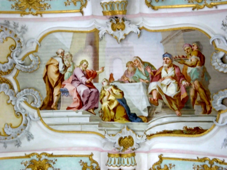 a painting in an ornate wall has several people sitting around