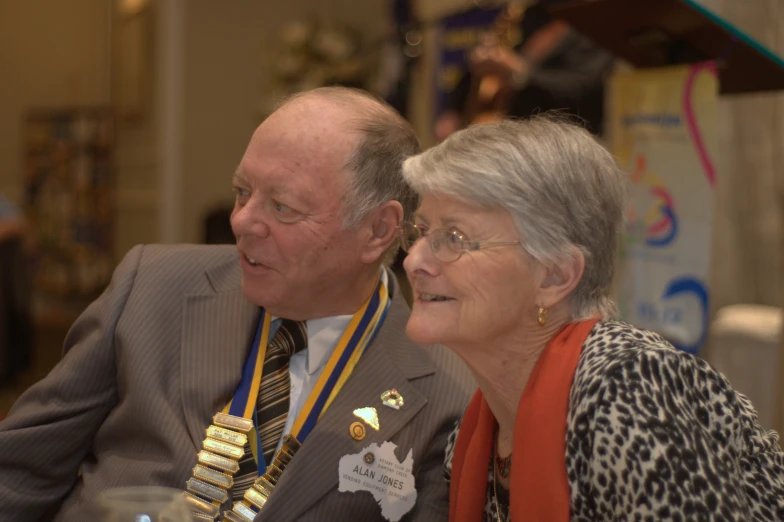 a man and woman sitting down with medals around their necks