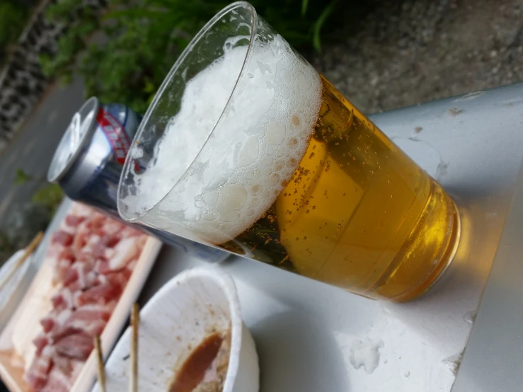 a glass with beer and two plates of meats on a table