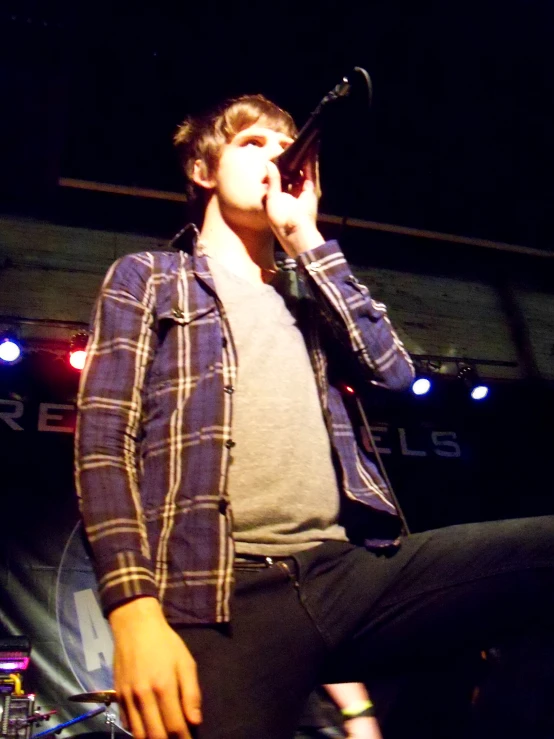 a man in plaid jacket holding a microphone and singing into a mic