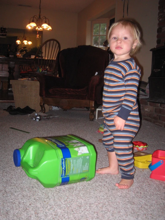 a child standing next to a green container on the floor