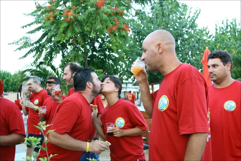 a group of men and women in red shirts eating a food line