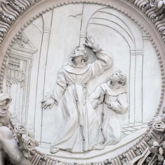 a stone work depicting a statue of jesus above two small statues