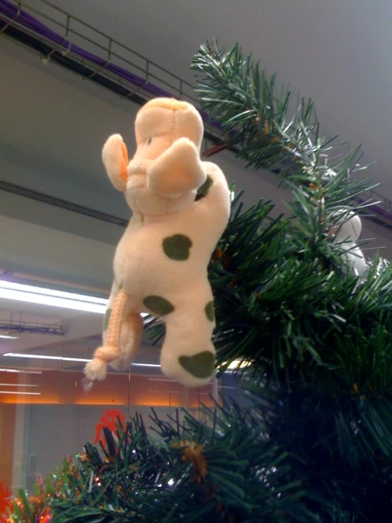 a green and white giraffe decoration hangs from a pine tree